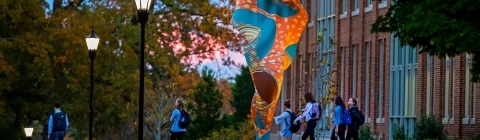 Students walk around the exterior of the Wall Center with Wind Sculpture in full view