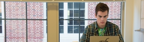 Study room of dorms where student does homework on his laptop