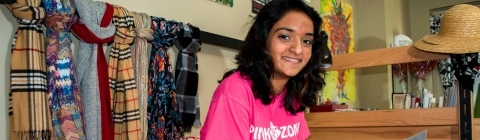 Student sits on her bed reading a book