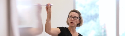 Anne Wills teaches class and writes on white board