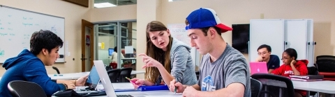 Students at Tutoring Center talk to one another and work on laptops