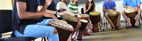 July Experience students drumming in big circle