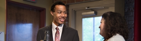 Student stands at podium with Kristin Booher to accept prize