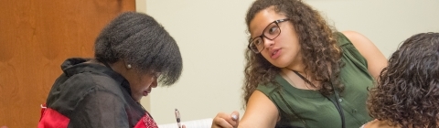 July Experience Classmates chat when one leans back towards the other at desks