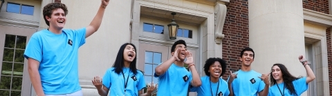 Students in July Experience shirts cheer on the steps of Chambers