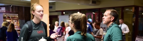 Student talks to volunteers from community organization at booth in Union