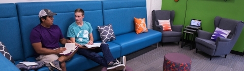 Two students talk while sitting on a couch