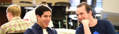 Students sit at table in the Library and study