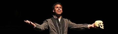 Performer on his knees sings a song while holding a skull