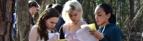 Three students look at analysis paperwork for environmental class assignment