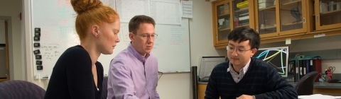 Mark Smith and two students sit around lab table and analyze data