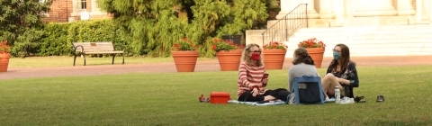 Three students on front lawn with masks