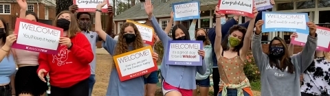 Students with masks holding signs for admitted students