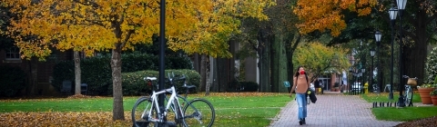 Student Walking on Campus with Mask in the Fall with Leaves Turning Orange