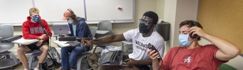 4 seated students using media equipment in Chambers class