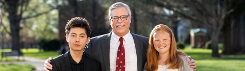 Prof. Emeritus Rich Neidinger outside with two student inductees on his left and right