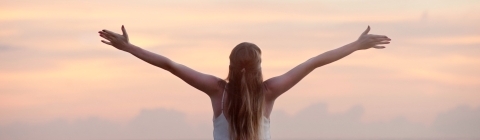 women with arms stretched out at beach stock