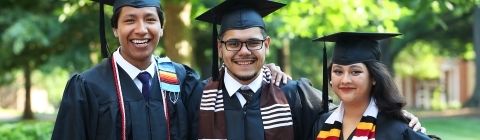 three students standing and smiling in graduation robes