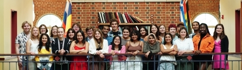 Group of students standing in front of brick wall smiling