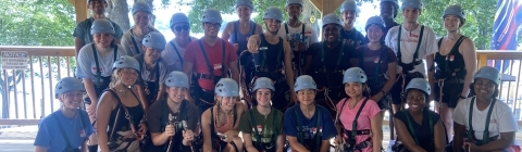 A group of students in harnesses and helmets smiling outside