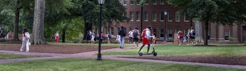 Students walking on campus with green trees in background