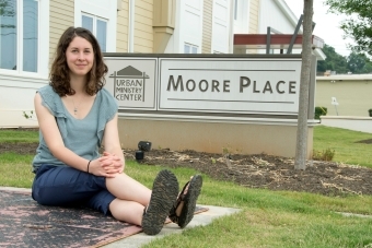 Elizabeth Welliver '16 sits on pavement next to the Moore Place community organization sign