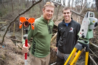 Prof. Brad Johnson and student stand in field with research equipment
