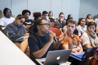 Classroom scene w student speaking at microphone