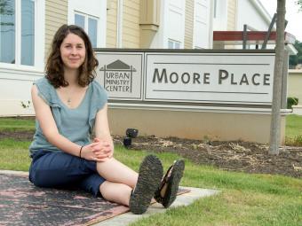 Elizabeth Welliver '16 sits on pavement next to the Moore Place community organization sign