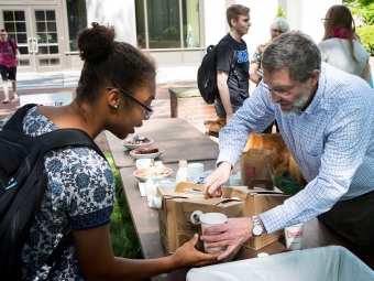 Chaplain Rob Spach serves coffee to student in the sculpture garden