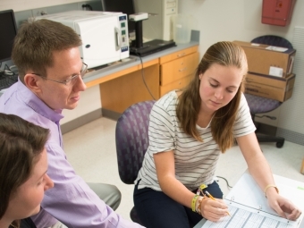 Mark Smith points to data while discussing with two students