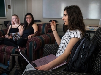 Three students sit on armchairs at the Carolina Inn and have a discussion