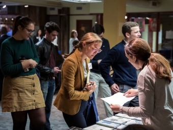 Group of students gather around a booth while one student talks to law school recruiter