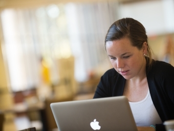 Student sits while looking at her laptop