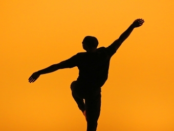 Student dances on stage and their silhouette is captured moving freely