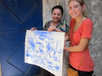 Student and Syrian artist hold watercolor painting.