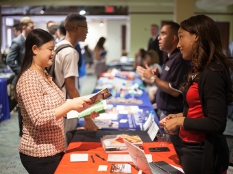 Recruiter talks to student at a booth at job fair