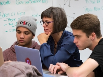 Two students chat with Prof. Churchill in class