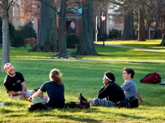 Students sit in a group on Chambers Lawn laughing 