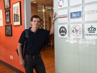 Student at his fellowship leans on glass wall with company logos