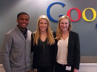 Three students stand in front of the Google sign during their internship