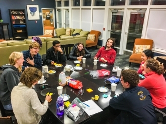 Interfaith dinner club shares dinner around a table smiling and laughing in conversation