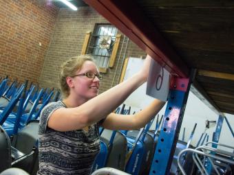Student in community-based learning course helps organize a warehouse with a mathematical algorithm and hangs signs up in warehouse