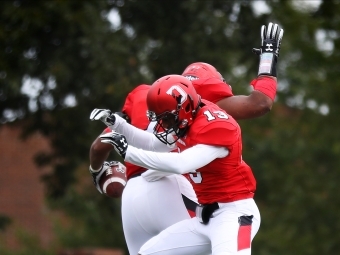 Two football players mid-jump in the air