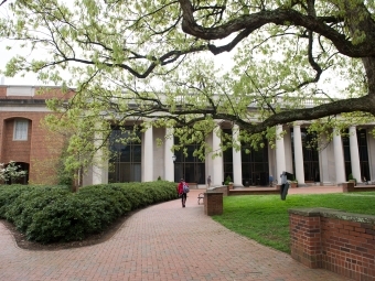 Student walking towards E.H. Little Library through blooming trees