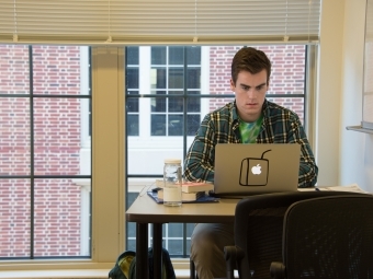 Study room of dorms where student does homework on his laptop