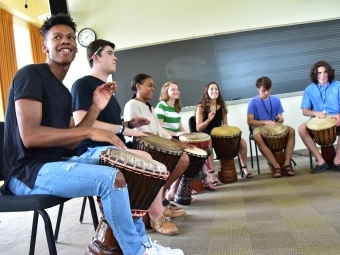 July Experience students drumming in big circle