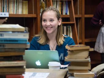 Student is surrounded by books and in front of her laptop