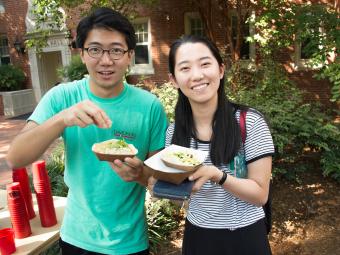 Students hold up food they are eating at an outside event