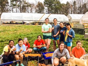 Farm volunteer students pose with vegetables they helped harvest